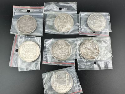 six pièces d'argent dans des sachets en plastique posées sur une surface noire