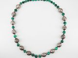 a close up of a necklace with green and silver beads