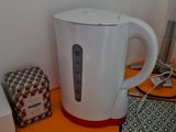 a white tea kettle sitting on a table next to a box of tea