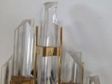 a glass vase with a gold base on top of a shelf
