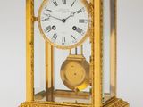 a gold clock with roman numerals and a glass case