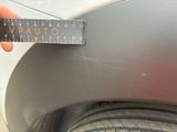 someone is measuring the width of a car ' s bumper with a ruler
