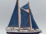 a model of a sailboat with blue sails on a wooden stand