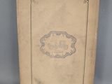an old book sitting on top of a table next to a gray wall