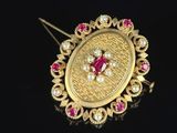 a close up of a gold broochle with pink and white stones