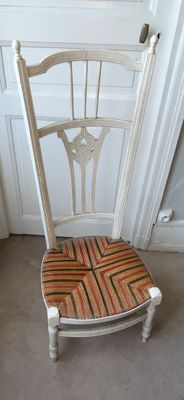 une chaise blanche posée à même le sol, avec un coussin rayé sur l'assise