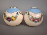 deux vases avec des fleurs peintes dessus, posés sur une table