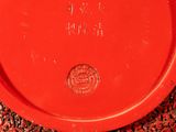 a red plate with a coin on it on a table
