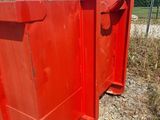 two red trash bins sitting on the side of the road