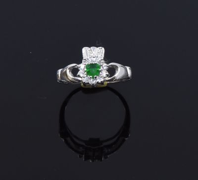 an emerald and diamond ring on a black surface
