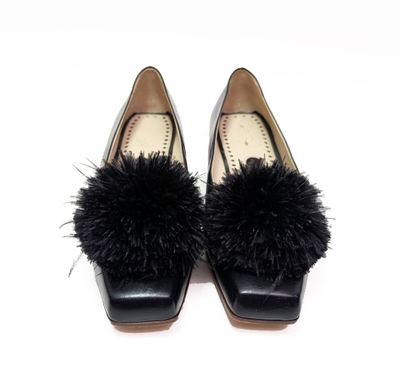 une paire de chaussures noires pour femme ornées de pompons en fourrure noire