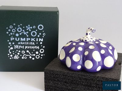 a purple and white polka dot pumpkin next to a black box