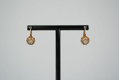 a pair of earrings on a black stand with a white background