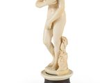 une figurine en ivoire représentant un garçon avec un chien, posée sur un socle