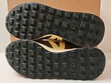 pair of black shoes with yellow soles sitting on top of a cardboard box