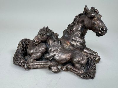 une statue d'un cheval et d'un poulain couchés sur le sol
