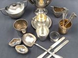 a silver tea set on a table with other silver items