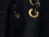 a close up of a black purse with a gold chain on it