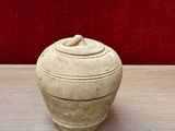 a white vase sitting on a table with a red wall in the background