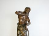 statue en bronze représentant un homme avec un serpent, posée sur un socle en marbre