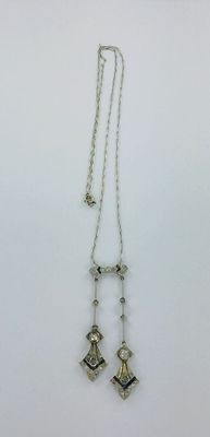 un collier en argent auquel sont suspendues deux clochettes