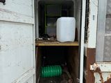 a white container in the back of a truck with a green hose