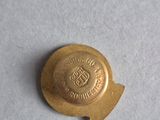 a close up of a gold button on a white surface