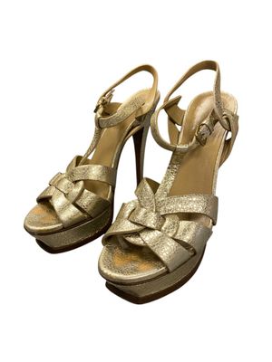 a close up of a pair of gold sandals on a white background