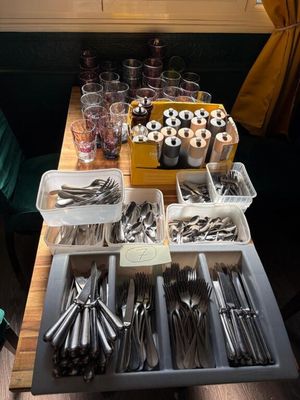 several trays of silverware on a wooden table in front of a window