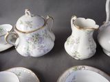 a table with a tea pot, cups, and saucers on it