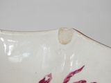 a close up of a white bowl with red paint on it