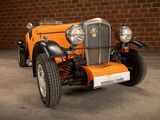 an orange car parked in front of a brick wall