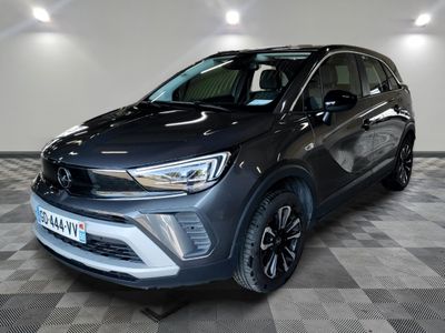 une voiture grise est garée dans une grande pièce au sol en damier