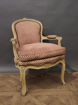 une chaise rose posée sur un parquet, près d'un mur gris