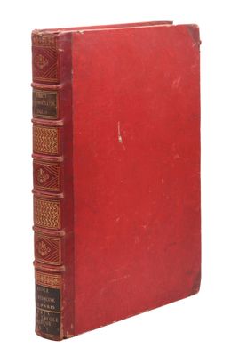 un vieux livre rouge posé sur une surface blanche