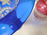 a blue glass bowl sitting on a table next to a red ornament