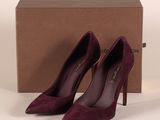 une paire d'escarpins violets posée sur une boîte