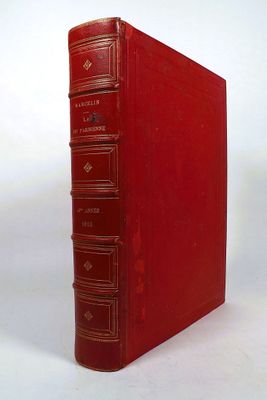 an old red book sitting on top of a white table