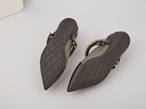 pair of women ' s black sandals with gold buckles on a white surface