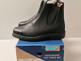 Les bottines Chelsea en cuir noir sont posées sur une boîte en carton