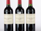 trois bouteilles de vin rouge posées l'une à côté de l'autre sur une surface blanche
