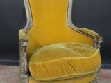 a yellow chair sitting on top of a carpeted floor next to a black wall