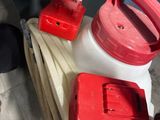 a red and white spray bottle and a hose on a cart