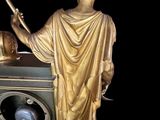 a gold statue of a man holding a globe and a clock