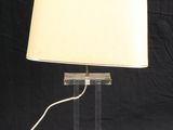une lampe de table en acrylique transparent, surmontée d'un abat-jour blanc