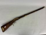 un vieux fusil avec une poignée en bois sur une surface blanche