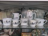 many cups and mugs on display in a glass case