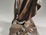 bronze statue of a woman holding a basket of flowers on a pedestal