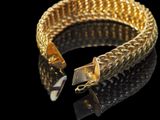 gold bracelet on a black surface with a black background