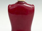 a red bottle with a wooden top on a white surface